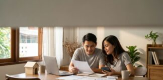 Cara Hitung Kemampuan Beli Rumah dari Gaji (2026) Pasangan menghitung cara hitung kemampuan beli rumah dari gaji dengan kalkulator dan laptop